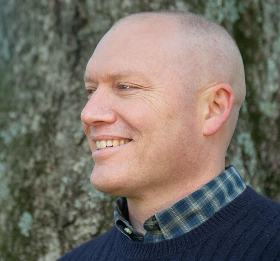 Author smiling in front of a tree